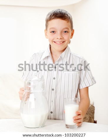 Child with glass pitcher milk. Boy drinking milk for breakfast