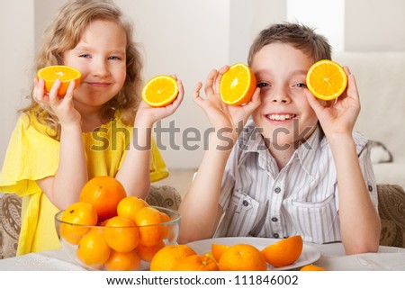 Children with oranges. Happy little girl and boy with fruit at home.