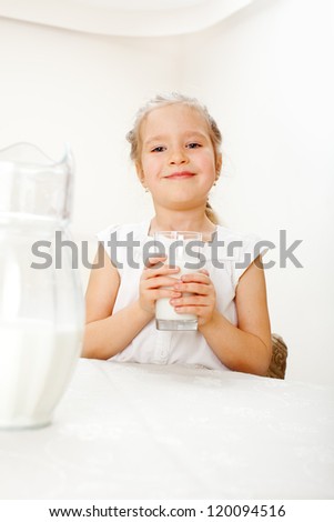Child with glass pitcher milk. Little girl drinking milk for breakfast