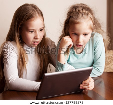 Children playing on tablet. Surprised kids looking at computer
