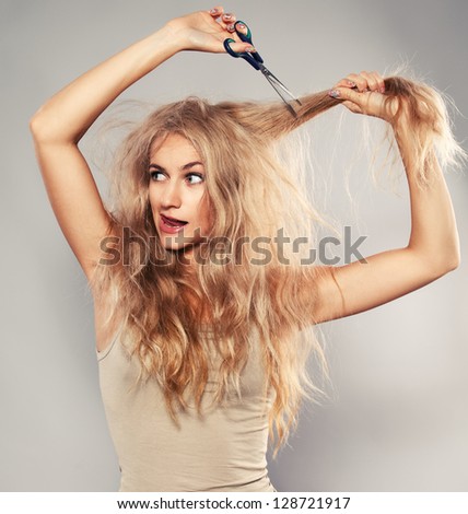 Young woman looking at split ends. Damaged long hair