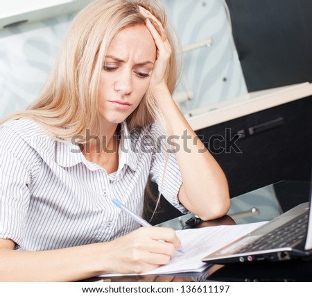 Female working at home. Sad woman looks at the bill.