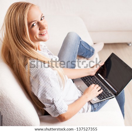Woman on the sofa with laptop. Happy female with computer at home