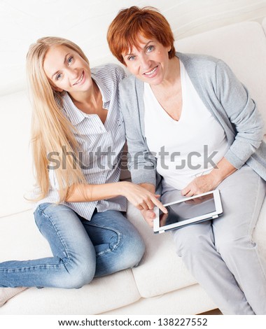 Mother and daughter wiht tablet at sofa. Two women with tablet computer. Family at home on sofa