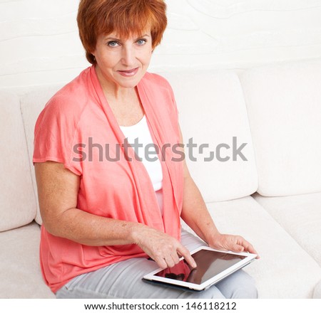 Mature woman with tablet pc. Female with computer at home