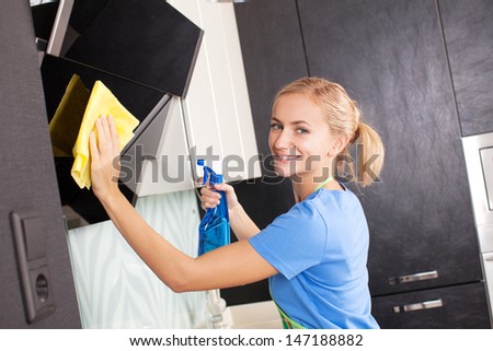 Woman cleaning kitchen. Young woman washing kitchen hood