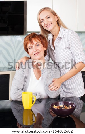Happy adult woman with daughter on kitchen. Family at home.