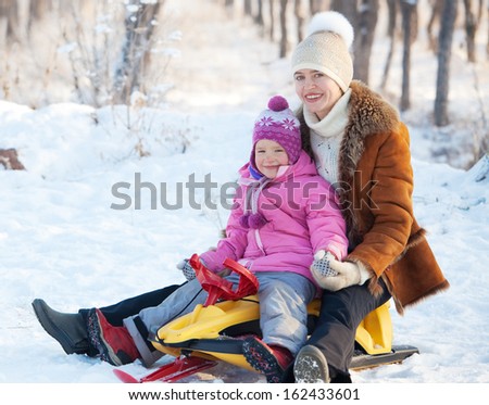 Family walking in a winter park. Parents with child on sled