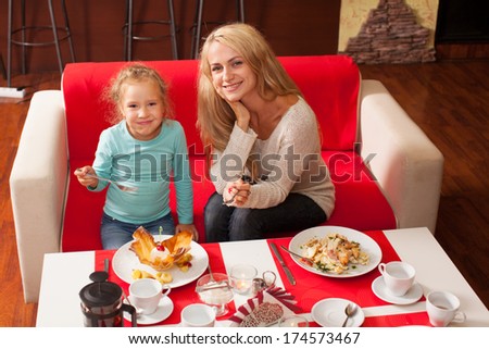 Happy family eating in restaurant. Mother and child in cafe