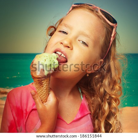 Child on the beach with ice cream. Girl at vacations on sea