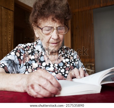 Old woman. Elderly female at home reading Book