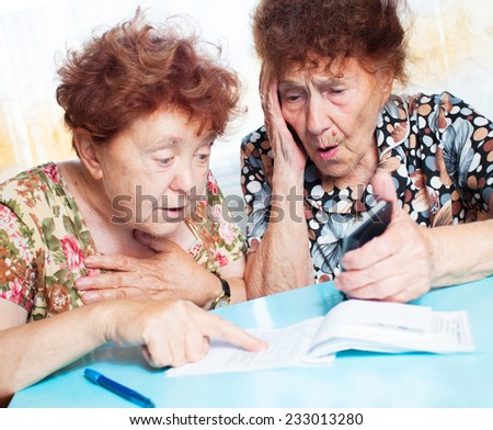 Two old women consider receipts. Surprised Female counts bill