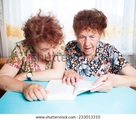 Two seniors. Old woman reading book. Friendship elderly