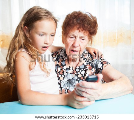 Senior with girl. Generation. Elderly woman with great-grandchild looking at mobile phone