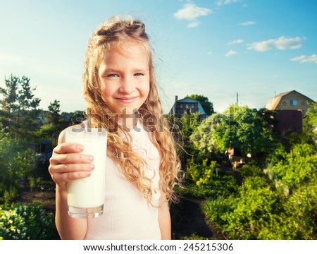 Girl holding glass with milk. Happy child at summer