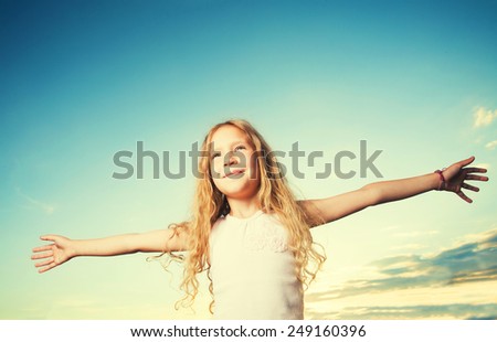 Child with arms outstretched. Freedom. Girl on a background of the sky