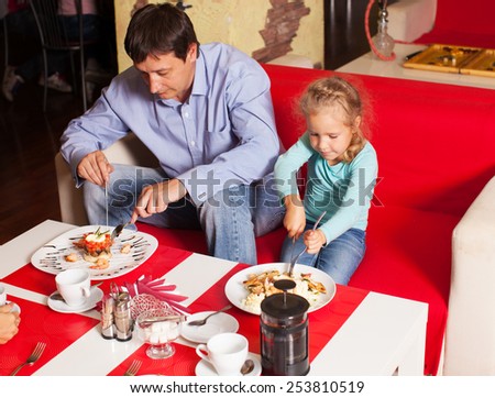 Happy family eating in restaurant. Father and child in cafe