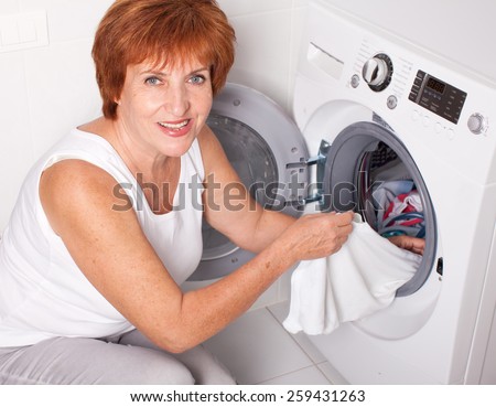 Woman puts clothes in the washing machine at home