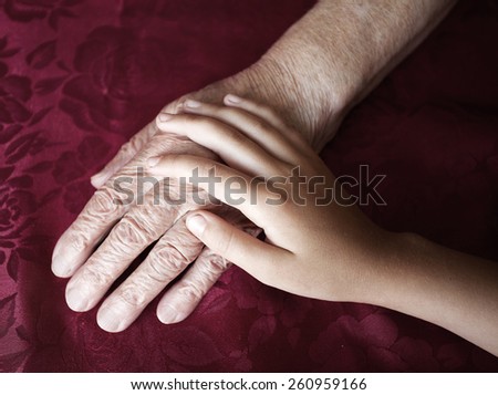 Two hands. Old and young. Child\'s hand on arm of an mature woman