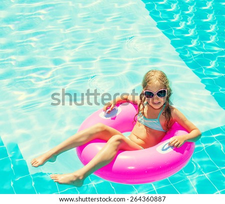 Girl on inflatable ring in swimming pool. Vacations