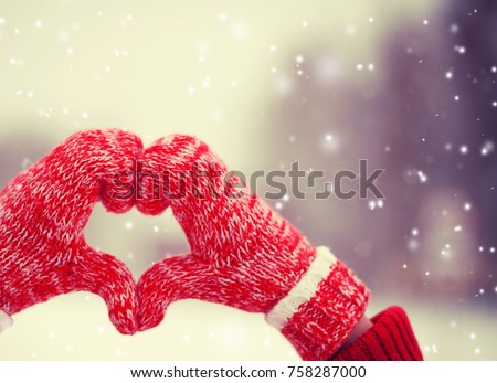Heart of mittens in snow. Knitted gloves in winter
