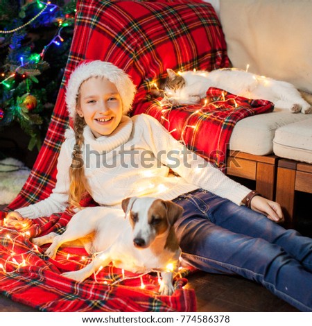 Smiling girl with dog and cat near christmas tree at home. Merry christmas and happy New year!