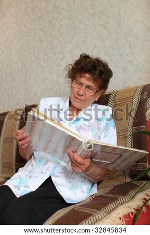 Lonely elderly woman looks a family picture album