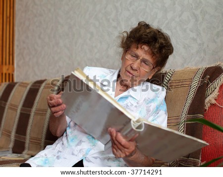 Lonely elderly woman looks a family picture album at home