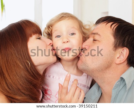 Portrait happy parents kissing the daughter