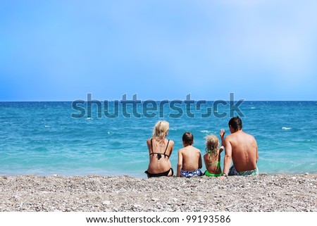 Happy family on the beach. Mother dad daughter and son sitting back on beach