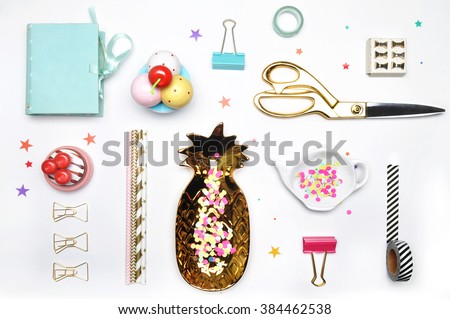 Flat lay. Accessories on the table, woman desk top. View top table, background mock up. Gold stationery,gold pineapple, mint box, colorful confettis, tea and strawberry.