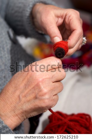 Closeup to craftsman\'s hand reeling thread to bobbin