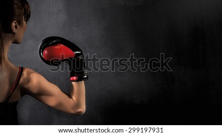 Woman Boxer Biceps with  Red Boxing Glove on Black Background, high contrast with saturated grunge filter