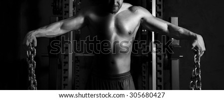 Close up of young muscular man lifting weights . Black and White High Contrast in Studio