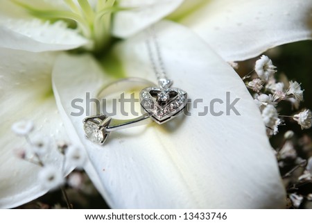 Diamond wedding ring and heart shaped necklace placed on flower petal