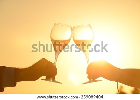 Hands of couple toasting at sunset