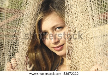 portrait of a blond woman looking through fishing net