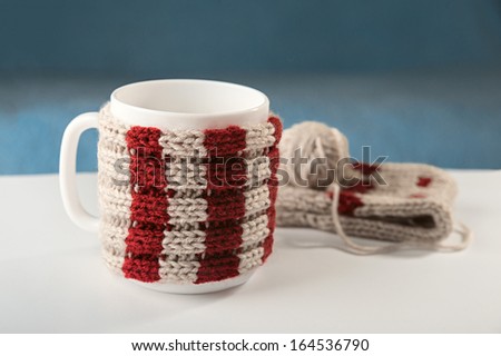 A cup of hot drink on the table, and next to a ball of yarn