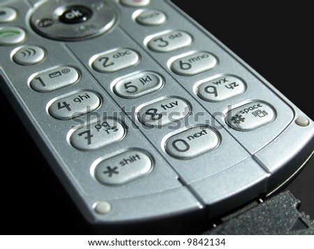 Close up photo of a silver cell phone number pad on a black background.