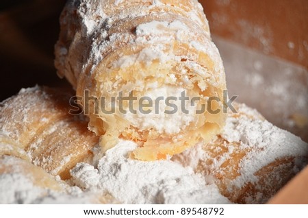Cream filled pastries covered in powdered sugar in a a brown box.