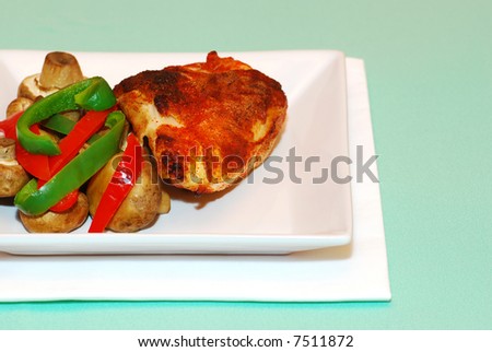 Fried chicken with mushrooms and peppers on a teal colored tablecloth