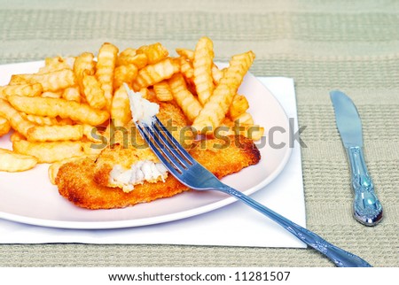 Fish and french fries with fish on a fork
