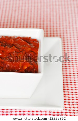 Texas style chili in a square bowl close up on a red and white checkered tablecloth