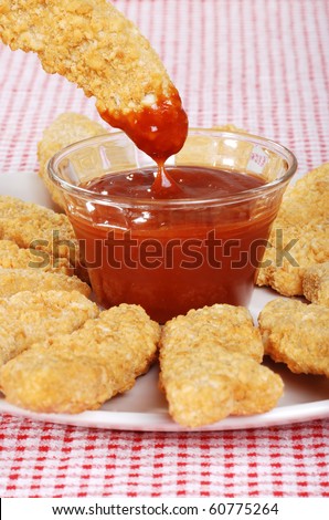 dipping chicken finger in BBQ sauce