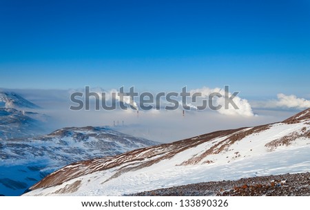 Mountain landscape with smoking factory chimneys. At the bottom of the dense fog.