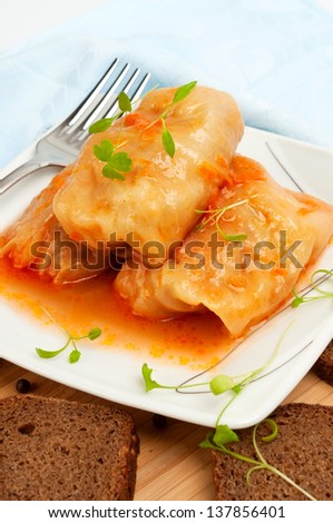 Cabbage rolls on a white plate with slices of rye bread