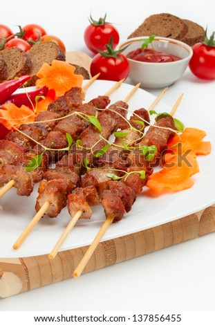 Pork skewers with cherry tomatoes, garlic and herbs. On a bamboo mat.