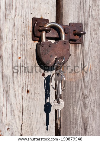 Rusty padlock with keys. On a wooden door.