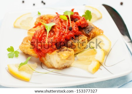 Grilled Fish with carrot pickle, decorated with lemon wedges.