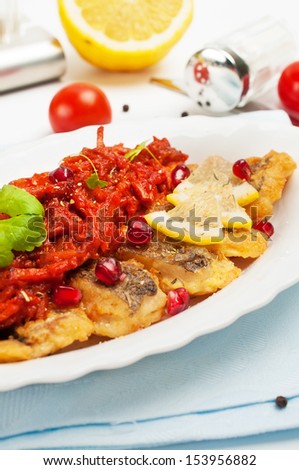 Pieces of fried fish with vegetable sauce with pomegranate seeds.